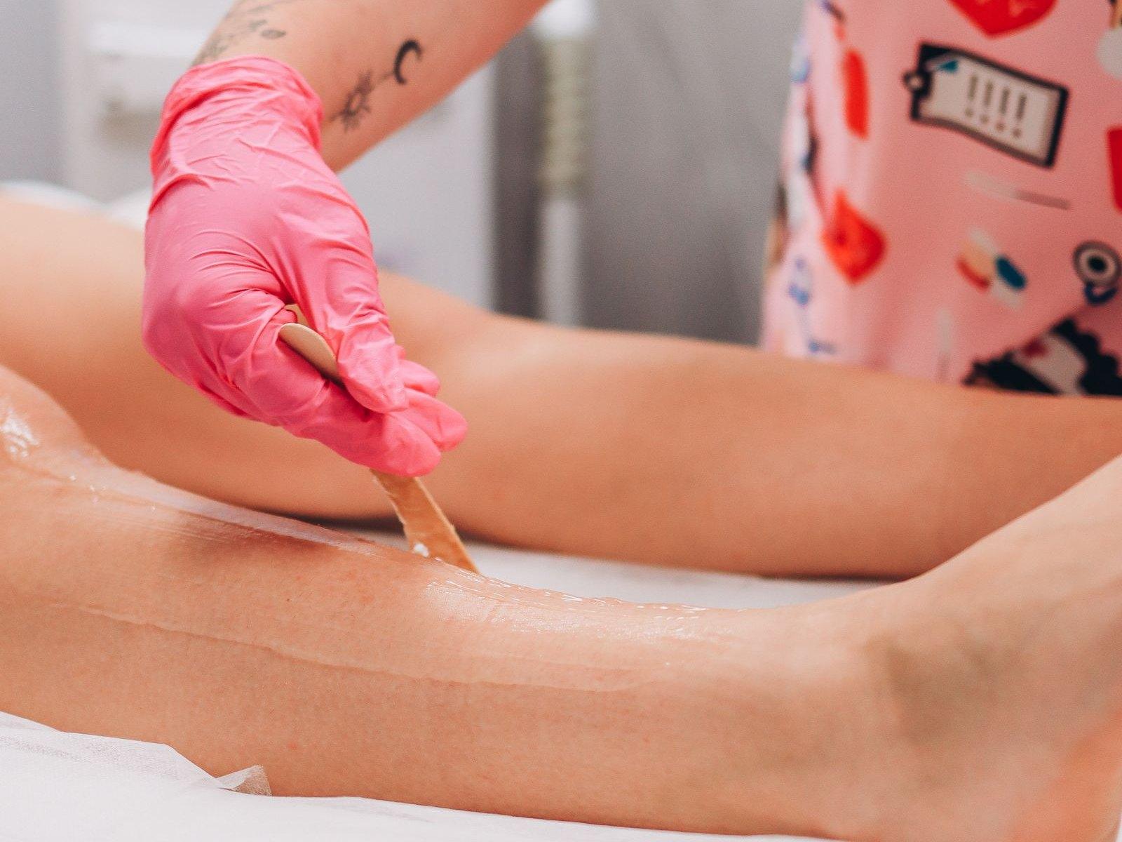 Strip wax being spread thinly along a leg with a spatula